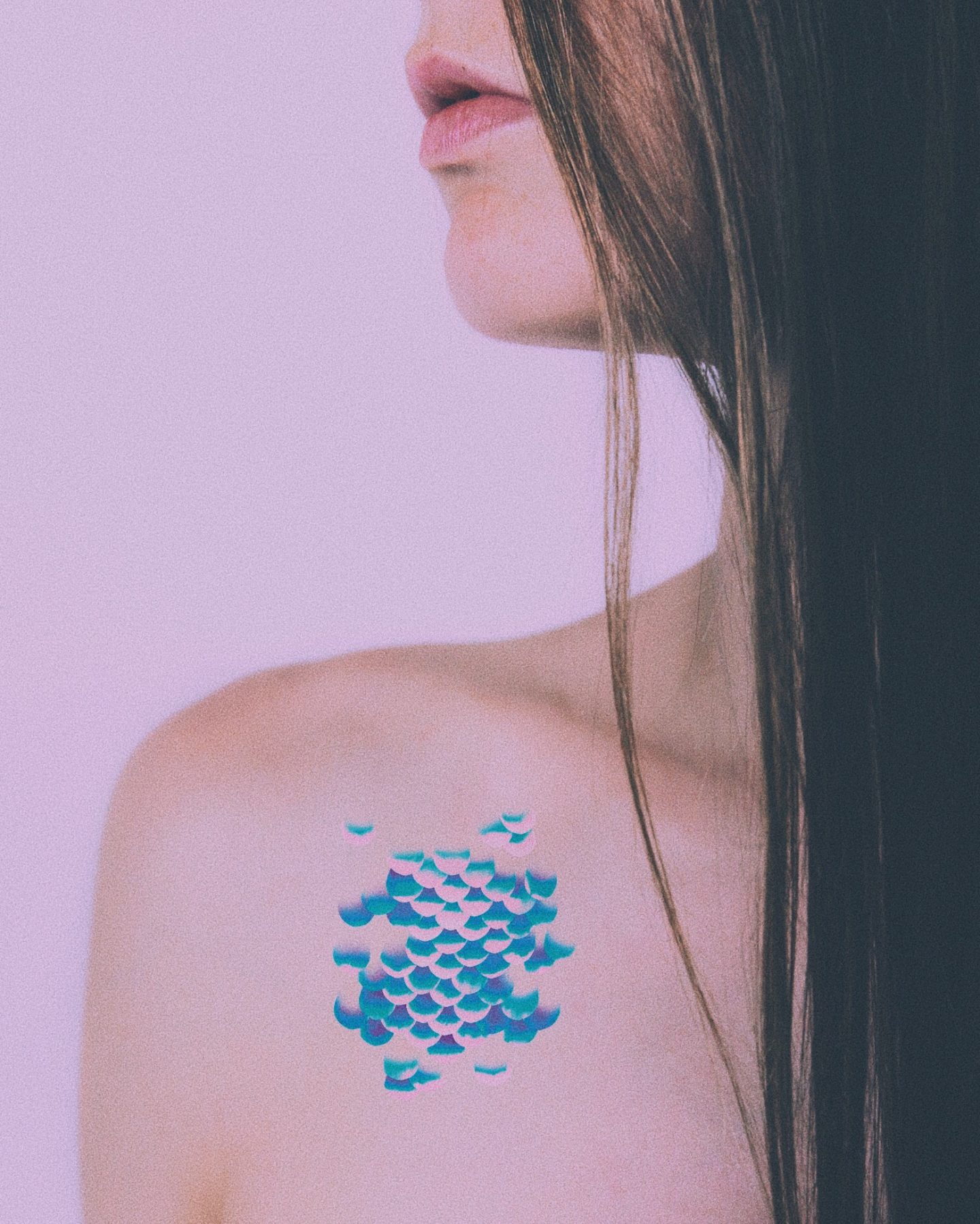 Woman with brown hair wearing mermaid scale temporary tattoos.