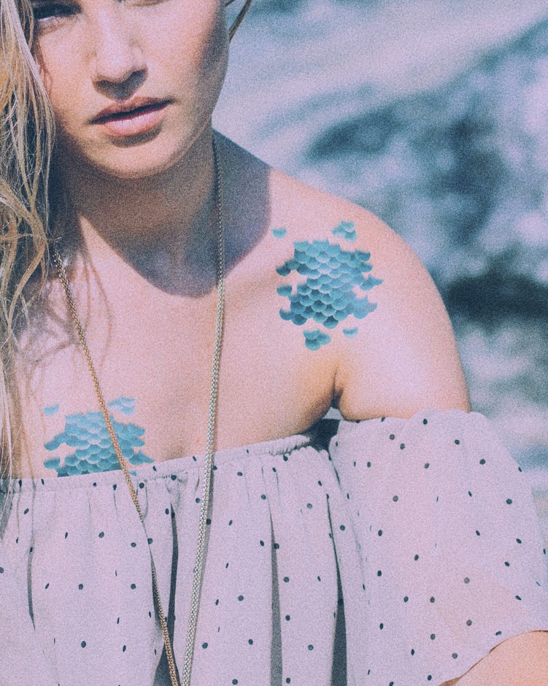 Woman wearing necklace and mermaid scale temporary tattoos.