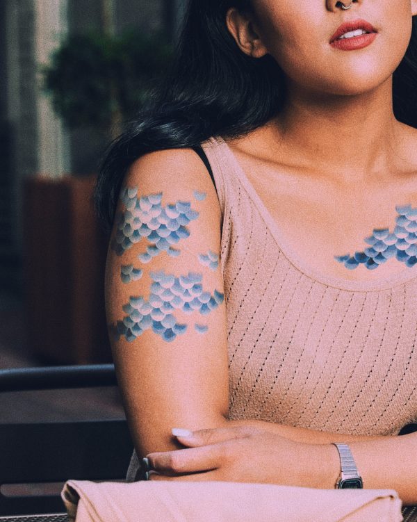 A woman at a coffee shop wearing mermaid scale temporary tattoos