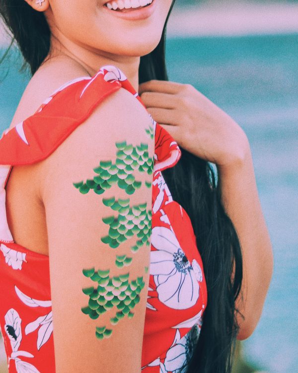A woman in a red dress wearing mermaid scale temporary tattoos